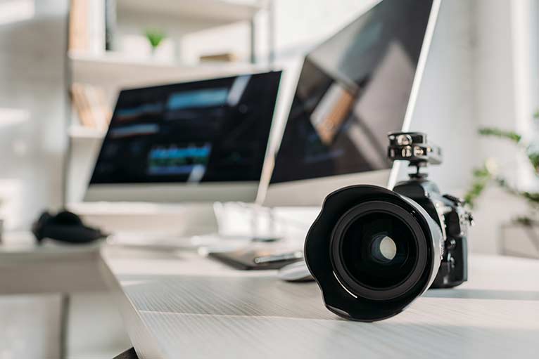 Appareil photo reflex sur bureau avec deux écrans d'ordinateur