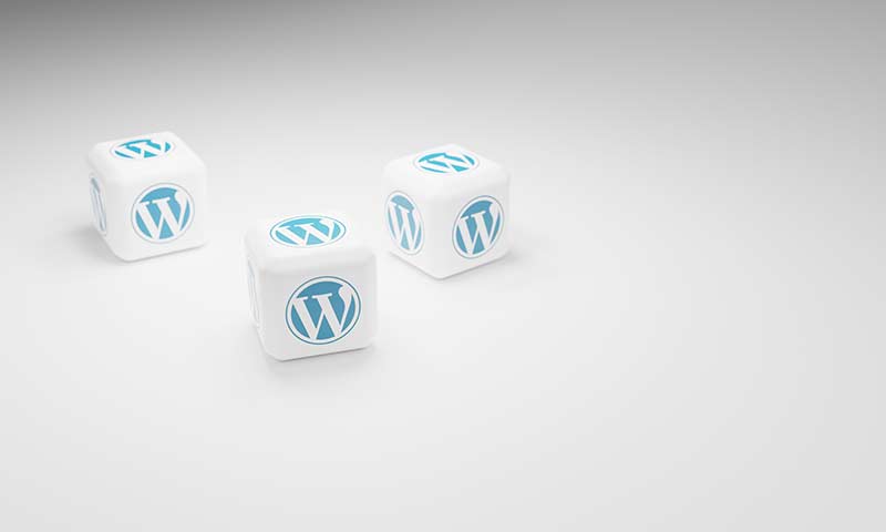 Trois dés blancs arborant le logo WordPress bleu